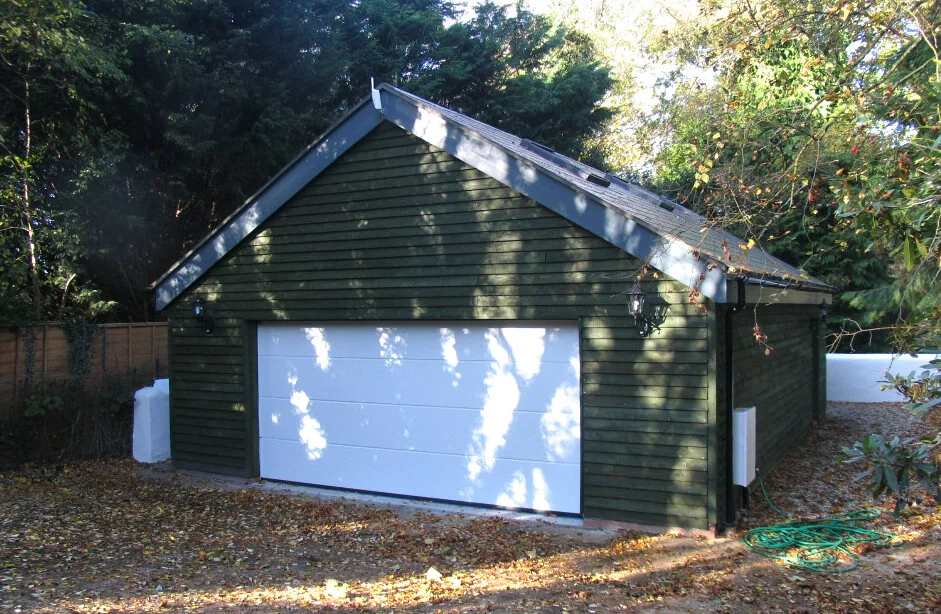 Timber clad garage outbuilding among trees