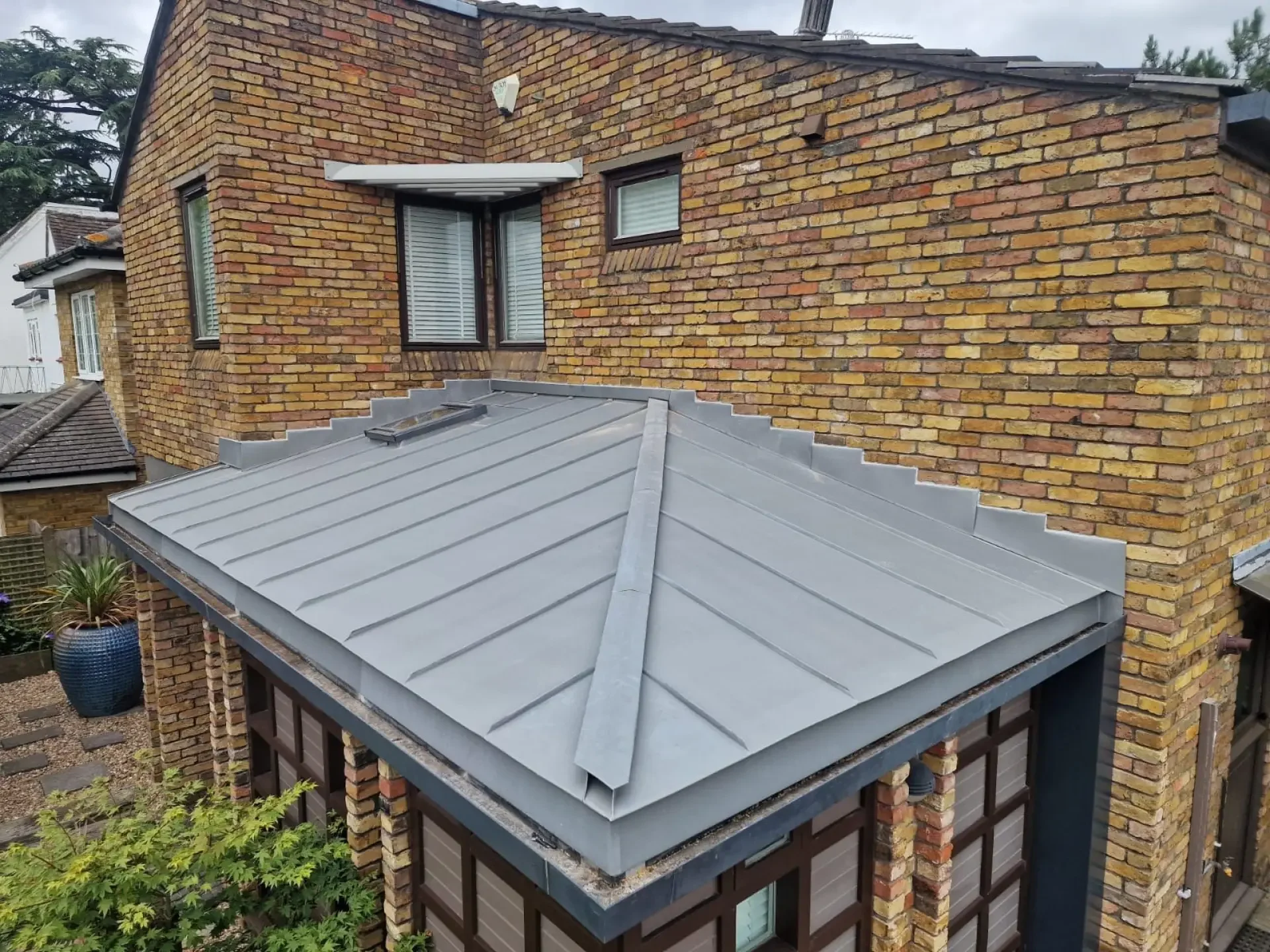 Grey standing seam zinc bay roof on a brick house in Putney