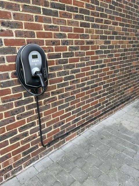 Wallbox installed on a brick wall beside a paved path