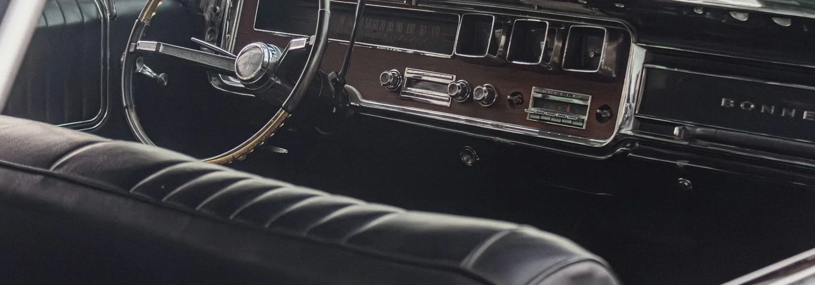Black leather bench seat and chrome dashboard in a classic car
