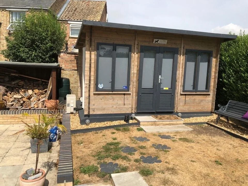 Timber garden office with an air conditioning outdoor unit beside it