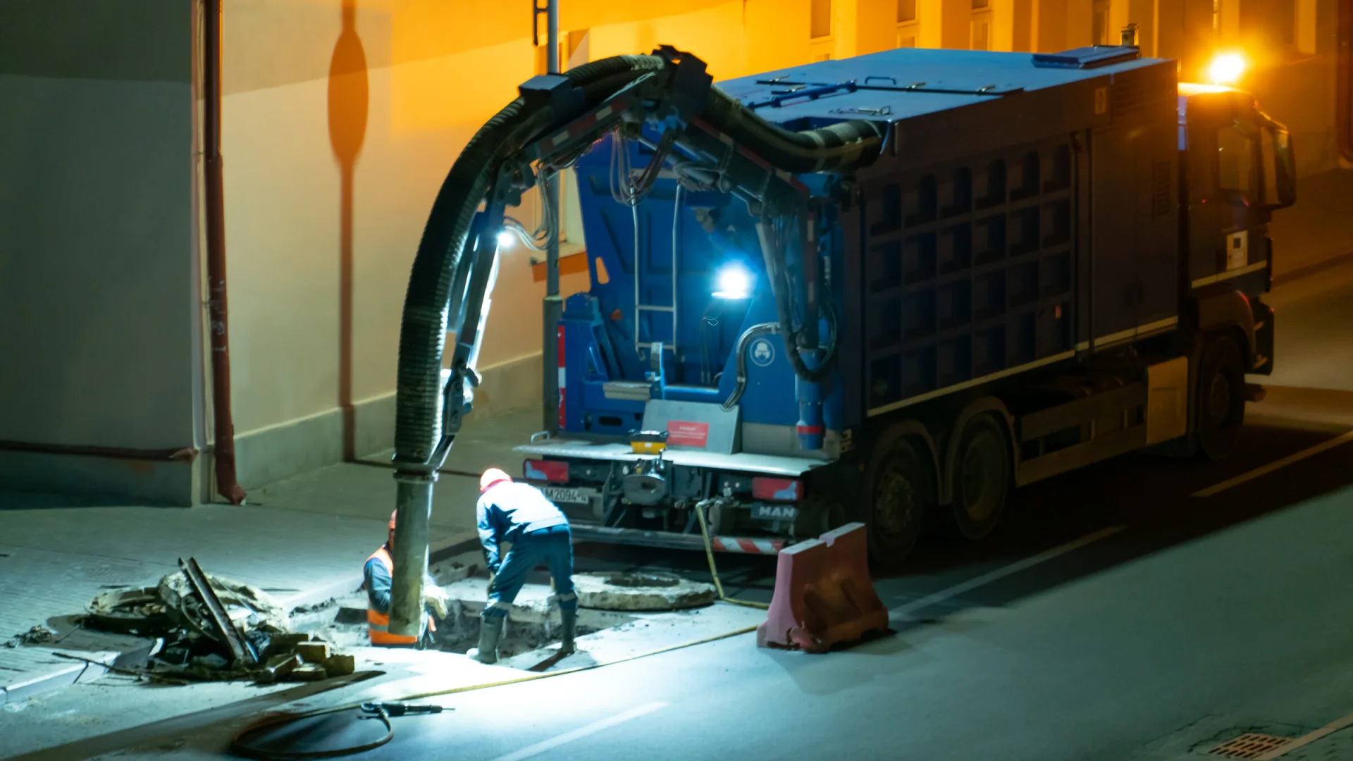 Emergency drainage crew working at an open manhole at night
