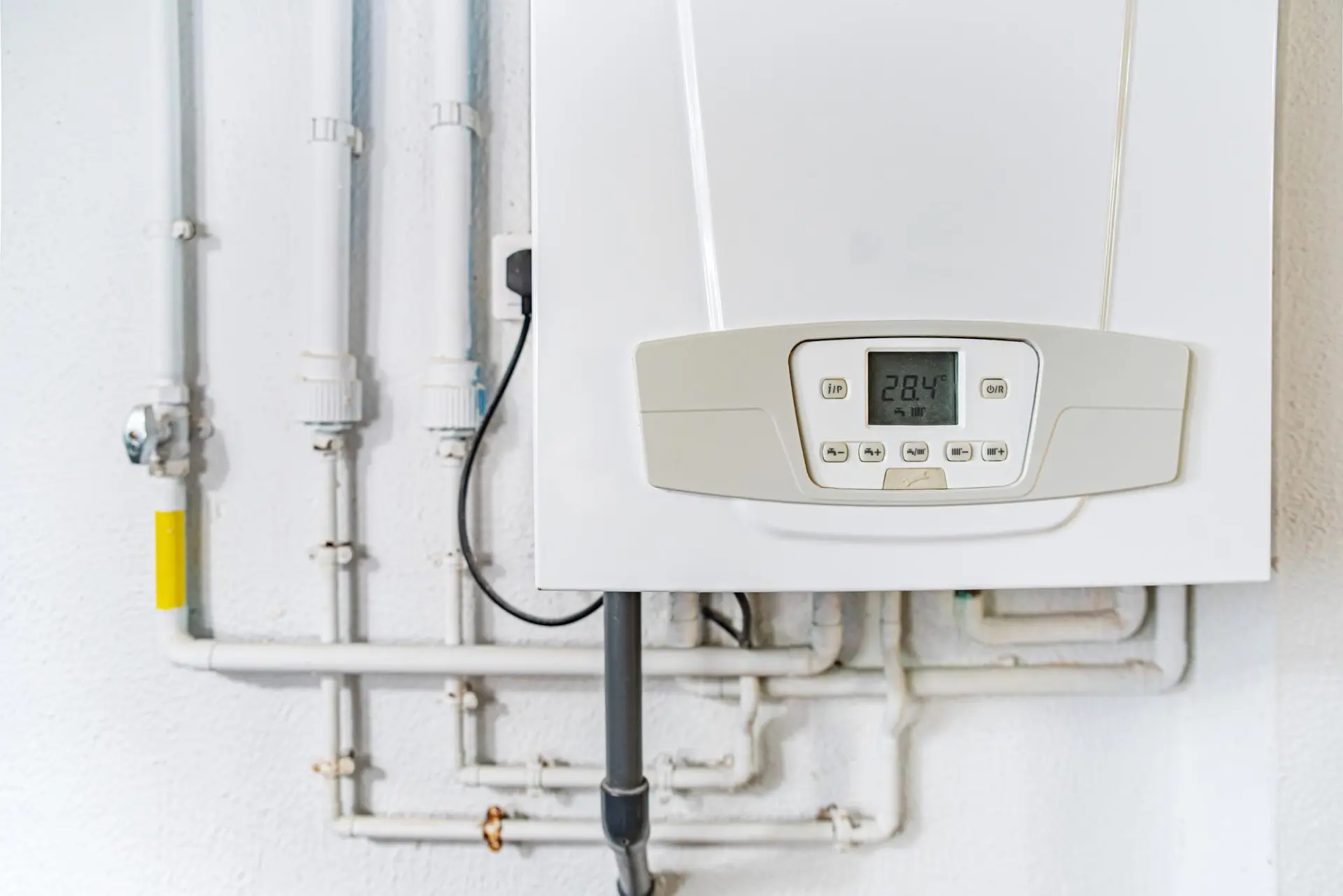 White wall-mounted boiler and heating pipework