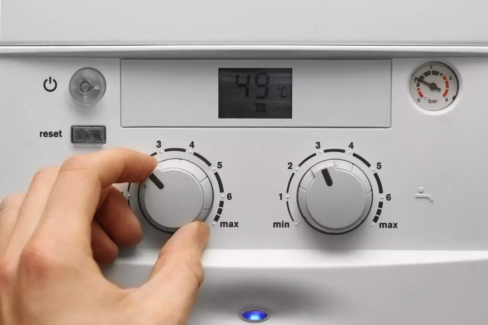 Close-up of a hand adjusting a boiler control