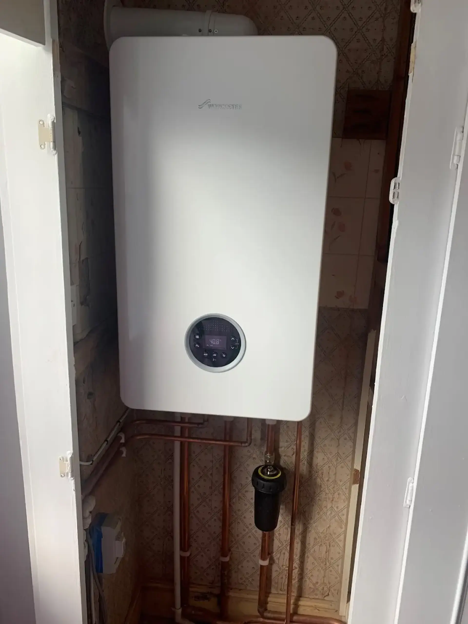 White wall-mounted boiler installed inside a cupboard