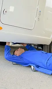 mechanic on floor inspecting underside of car
