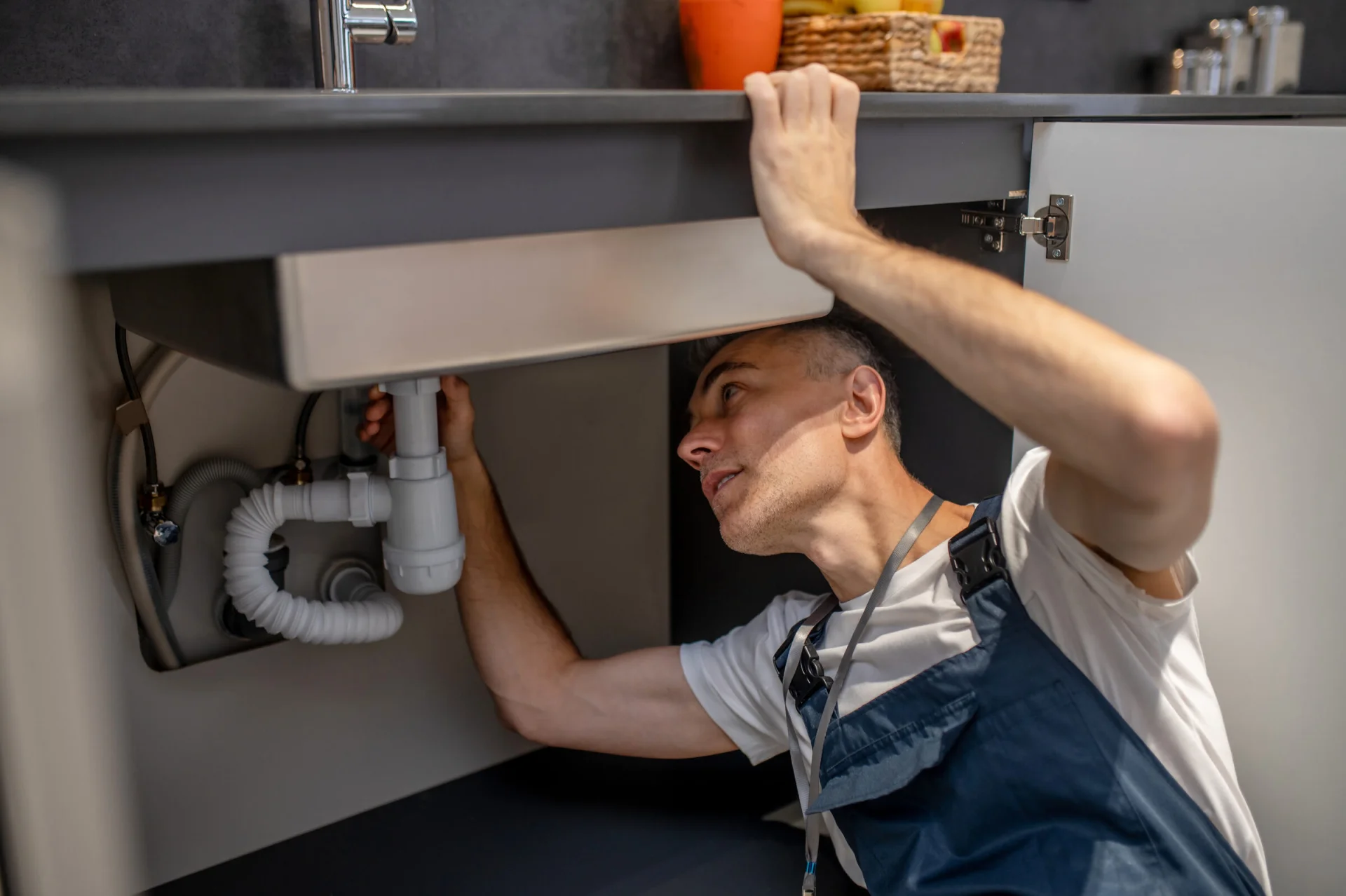Plumber checking pipework beneath a kitchen sink
