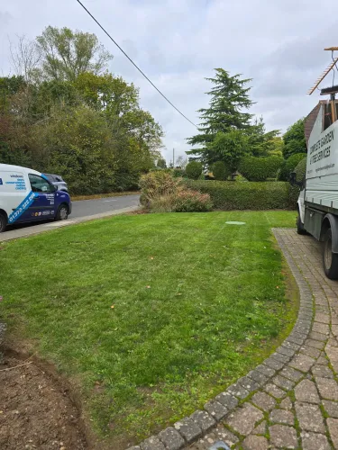 Freshly mown front lawn with the MH Garden and Tree Services vans parked at the roadside
