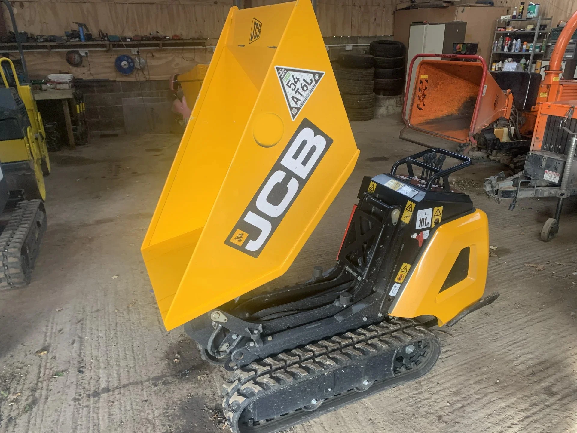 Yellow tracked dumper with its skip raised in the hire workshop