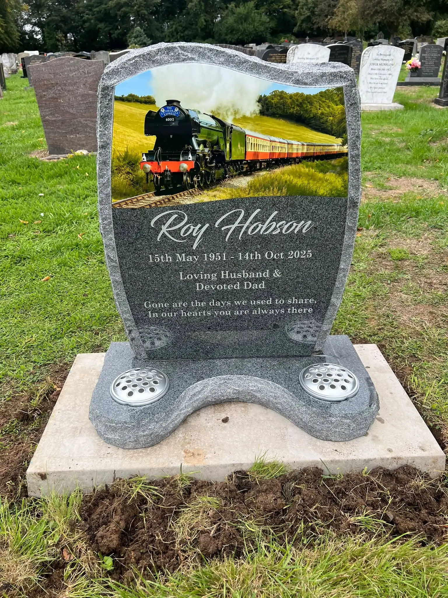 Installed mid-grey granite lawn headstone with a personalised train design
