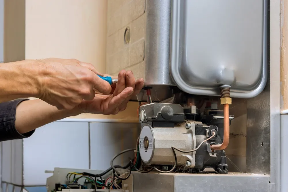 Engineer repairing the inside of a gas boiler with a screwdriver