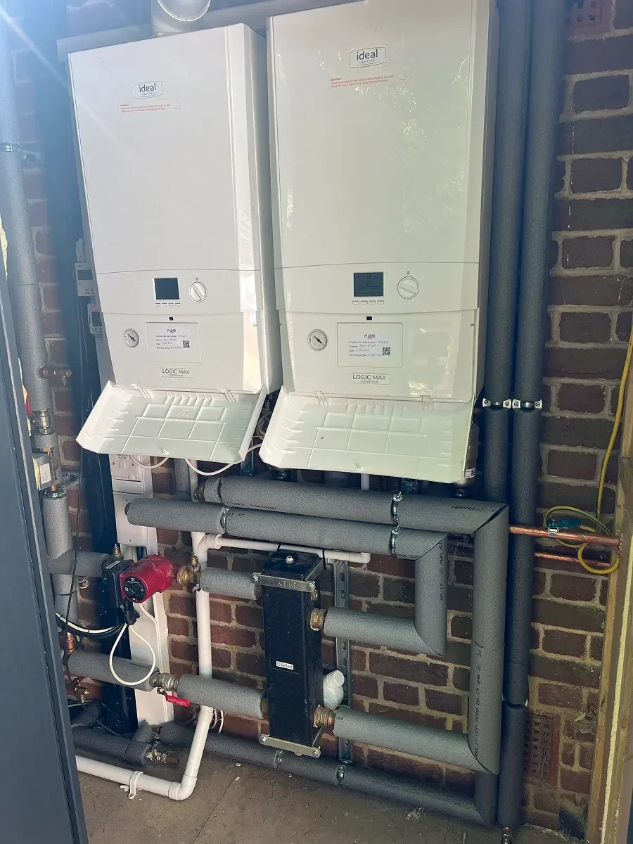 Two wall-hung boilers fitted side by side in a plant room